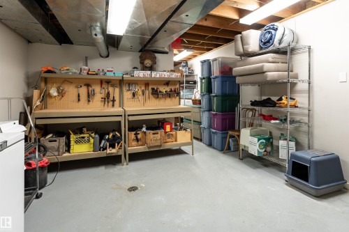The property includes a utilitarian space with exposed ceiling joists and ductwork, featuring a light grey floor and overhead fluorescent lighting - 9715 141 Street Nw, Edmonton, AB - Indoor