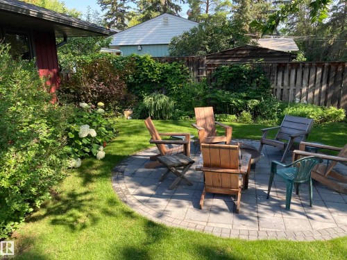 The property features a well-maintained lawn and a paved patio area - 9715 141 Street Nw, Edmonton, AB - Outdoor With Deck Patio Veranda With Backyard