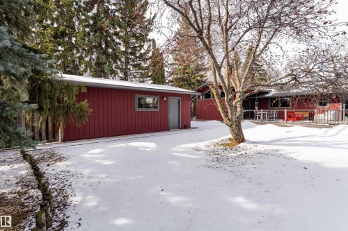 The property features a red exterior, a deck, and an extensive yard with mature trees - 9715 141 Street Nw, Edmonton, AB - Outdoor