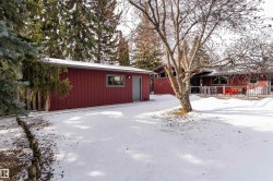 The property features a red exterior, a deck, and an extensive yard with mature trees - 