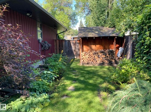 The property features a well-maintained lawn with stepping stones, bordered by various plantings - 9715 141 Street Nw, Edmonton, AB - Outdoor