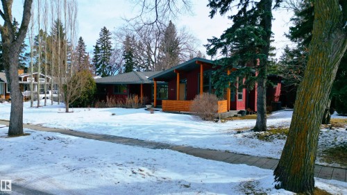 The property features a modern ranch-style home with a dark red exterior, a gray roof, and a wooden porch - 9715 141 Street Nw, Edmonton, AB - Outdoor