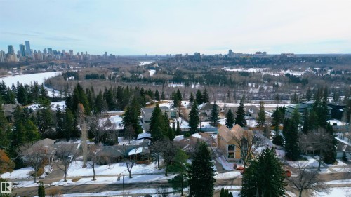 The property is located in a community featuring residential streets with homes, mature trees, and a distant city skyline - 9715 141 Street Nw, Edmonton, AB - Outdoor With View
