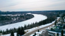 Aerial view showcasing the expansive frozen river, bordered by a dense forest - 