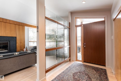 Inviting entryway featuring a wood front door with a sidelight, light wood flooring, and a decorative partition with frosted and clear glass panels - 9715 141 Street Nw, Edmonton, AB - Indoor Photo Showing Other Room