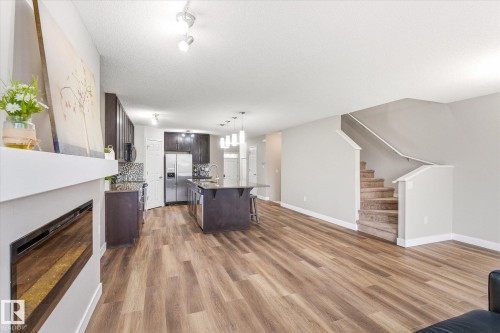 This open-concept living area features hardwood style flooring and light-colored walls - 1668 Chapman Way, Edmonton, AB - Indoor Photo Showing Living Room With Fireplace