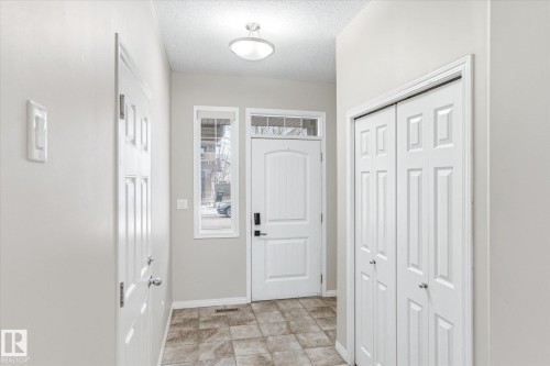 Entryway featuring tiled flooring, a front door with an overhead transom window, and a white bi-fold closet - 1668 Chapman Way, Edmonton, AB - Indoor Photo Showing Other Room