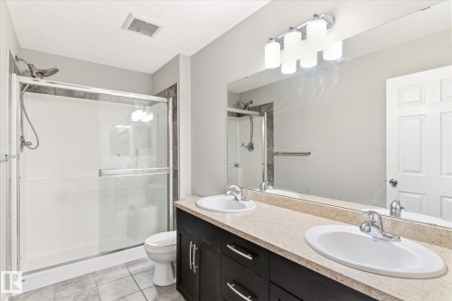 Bathroom featuring a shower with sliding glass doors, a vanity with two sinks, and a large wall-mounted mirror - 1668 Chapman Way, Edmonton, AB - Indoor Photo Showing Bathroom