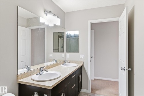 Bathroom featuring a double vanity with two sinks, two mirrors, and overhead lighting - 1668 Chapman Way, Edmonton, AB - Indoor Photo Showing Bathroom
