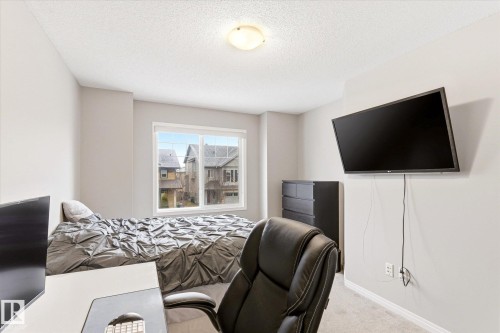 This room features light-colored walls and carpeting, a window providing natural light, and a ceiling-mounted light fixture - 1668 Chapman Way, Edmonton, AB - Indoor Photo Showing Bedroom