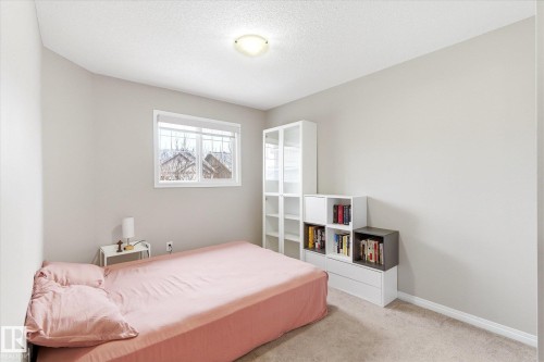 This room features light-colored walls and carpeting, a window providing natural light, and a ceiling light fixture - 1668 Chapman Way, Edmonton, AB - Indoor Photo Showing Bedroom