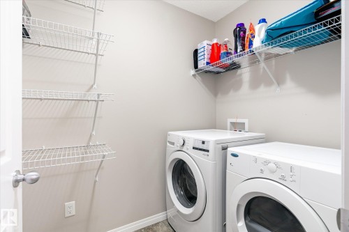 Dedicated laundry area featuring a washer and dryer, along with wall-mounted shelving for storage - 1668 Chapman Way, Edmonton, AB - Indoor Photo Showing Laundry Room