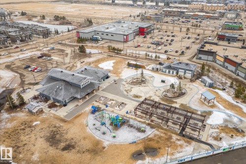 Aerial view showcasing the community grounds with a central building, structured play areas, and surrounding commercial establishments - 1668 Chapman Way, Edmonton, AB - Outdoor With View