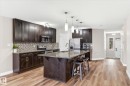 The kitchen features dark wood cabinetry, a mosaic tile backsplash, and stainless steel appliances - 1668 Chapman Way, Edmonton, AB  - Indoor Photo Showing Kitchen With Upgraded Kitchen 