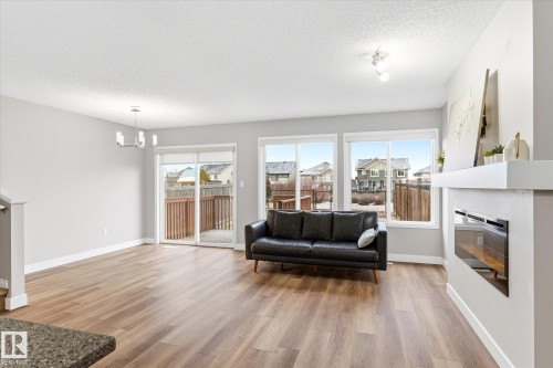 The property features light wood flooring, light grey walls, and a contemporary fireplace - 1668 Chapman Way, Edmonton, AB - Indoor Photo Showing Living Room With Fireplace