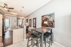 The kitchen features a breakfast bar with a sink, a black refrigerator, and dark hardwood flooring - 