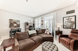The living area features light-colored walls, large windows, and a built-in desk unit - 