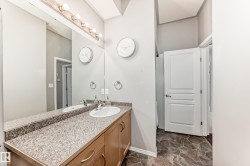 The bathroom features a vanity with a countertop, an integrated sink, and a large mirror with overhead lighting - 