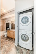 Convenient laundry area with a stacked washer and dryer, complemented by patterned floor tiling - 