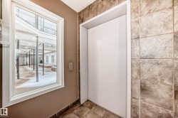 The property features a window providing views of a covered outdoor walkway and courtyard area, alongside an elevator with tiled walls and flooring - 