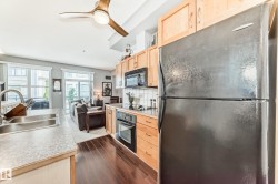 The kitchen features wooden cabinetry, a dark finished refrigerator, and a built-in microwave - 