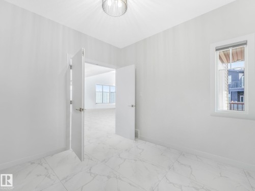 This room features light-colored walls, white tile flooring with a marble-like pattern, and a modern ceiling light fixture - 1104 152 Avenue, Edmonton, AB - Indoor Photo Showing Other Room
