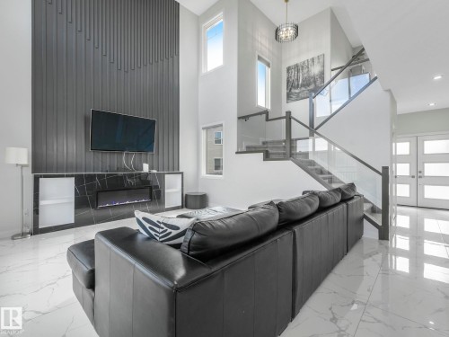 Living area featuring high ceilings, a fireplace with a black marble surround, and white tiled flooring - 1104 152 Avenue, Edmonton, AB - Indoor