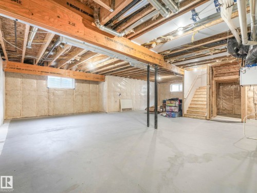 Expansive unfinished space featuring exposed ceiling joists, concrete flooring, and a visible wooden staircase - 1104 152 Avenue, Edmonton, AB - Indoor Photo Showing Basement