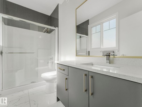 Bathroom featuring a modern vanity with a rectangular sink, a glass-enclosed shower, a large mirror, and a window - 1104 152 Avenue, Edmonton, AB - Indoor Photo Showing Bathroom