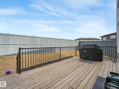 The property features a wooden deck with a black metal railing, overlooking a fenced yard - 1104 152 Avenue, Edmonton, AB - Outdoor With Deck Patio Veranda