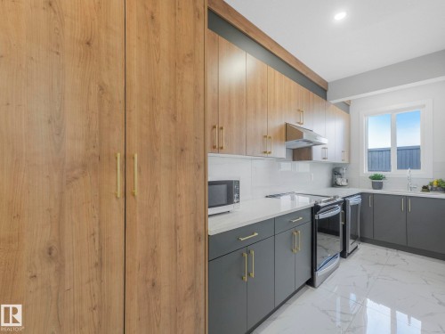 Kitchen featuring light wood tone upper cabinetry, dark gray lower cabinetry, and white countertops - 1104 152 Avenue, Edmonton, AB - Indoor Photo Showing Kitchen
