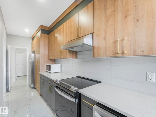 The kitchen features sleek wood-grain upper cabinetry, dark grey base cabinets, and light grey countertops - 1104 152 Avenue, Edmonton, AB - Indoor Photo Showing Kitchen