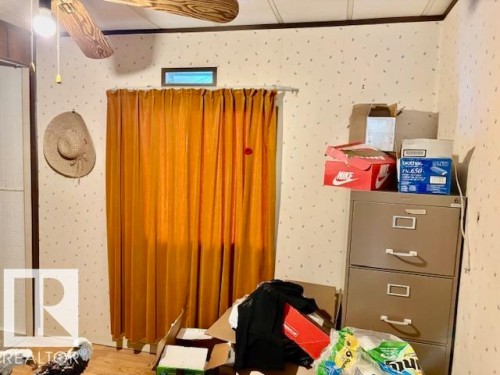 The room features light-colored wallpaper with a subtle pattern and a ceiling fan with wooden-style blades - 4809 53 Ave, Willingdon, AB - Indoor