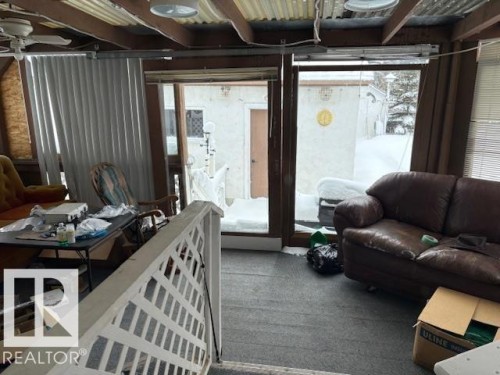 The property features a sunroom with an exposed beam ceiling, corrugated metal ceiling panels, and large glass doors - 4809 53 Ave, Willingdon, AB - Indoor