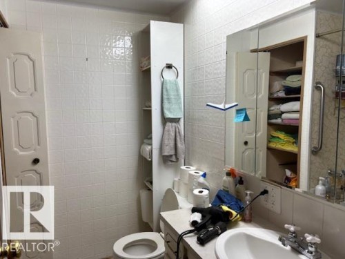 Bathroom featuring white tiled walls, a vanity with an integrated sink, and an overhead medicine cabinet with mirrored doors - 4809 53 Ave, Willingdon, AB - Indoor Photo Showing Bathroom