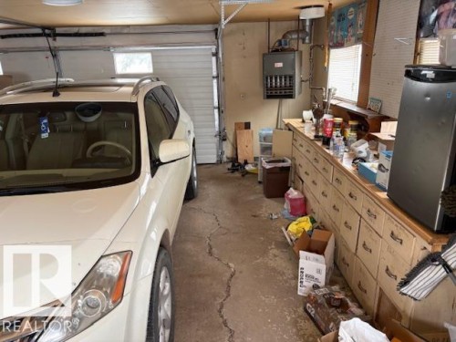 The property includes a spacious garage with a white sectional door and an overhead light fixture - 4809 53 Ave, Willingdon, AB - Indoor Photo Showing Garage
