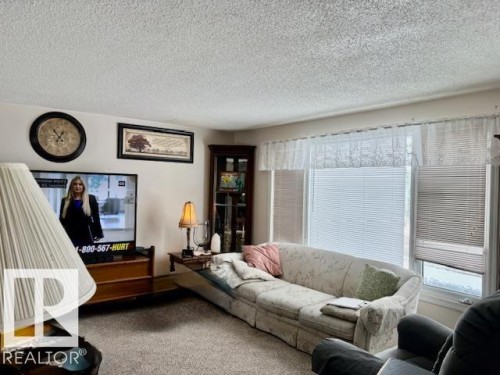 Living area featuring carpeted flooring, a large window with blinds, and white walls - 4809 53 Ave, Willingdon, AB - Indoor Photo Showing Living Room