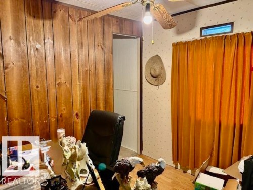 This room features wood paneling on one wall, a ceiling fan with light fixture, and a window with curtains - 4809 53 Ave, Willingdon, AB - Indoor