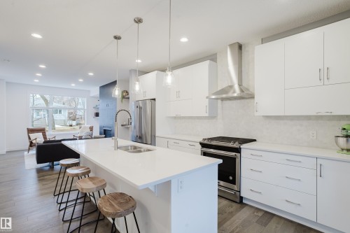 Open concept kitchen featuring an island with a sink, white cabinetry, and stainless steel appliances - 9612 72 Avenue, Edmonton, AB - Indoor Photo Showing Kitchen With Double Sink With Upgraded Kitchen