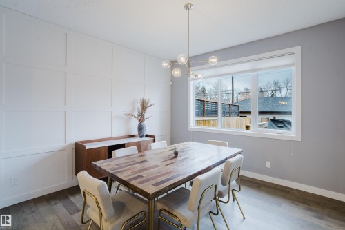 The dining area features light-colored walls, a prominent window with white trim, and a contemporary light fixture - 9612 72 Avenue, Edmonton, AB - Indoor Photo Showing Dining Room