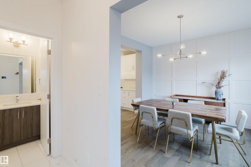 The dining area features a modern chandelier, wainscoting on one wall, and hardwood flooring - 9612 72 Avenue, Edmonton, AB - Indoor Photo Showing Dining Room
