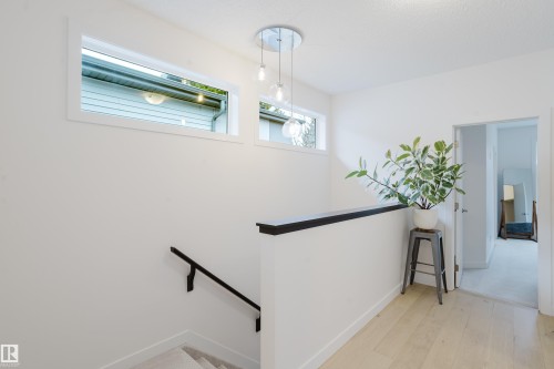 Bright hallway with light hardwood floors, white walls, and a modern ceiling light fixture - 9612 72 Avenue, Edmonton, AB - Indoor Photo Showing Other Room