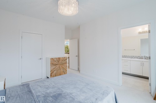 This room features white walls, a contemporary ceiling light fixture, and an entryway leading into a bathroom with a vanity and mirror - 9612 72 Avenue, Edmonton, AB - Indoor Photo Showing Bedroom