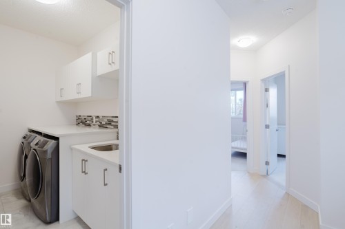 Dedicated laundry area featuring white cabinetry, a countertop, and a utility sink - 9612 72 Avenue, Edmonton, AB - Indoor Photo Showing Laundry Room