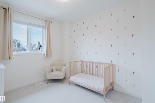 This room features a window with natural light, light-colored carpeting, and a decorative wall with floral accents - 9612 72 Avenue, Edmonton, AB - Indoor Photo Showing Bedroom