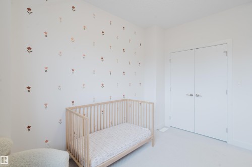 Bedroom featuring light-colored walls with decorative floral accents, light-colored carpeting, and a double-door closet - 9612 72 Avenue, Edmonton, AB - Indoor Photo Showing Other Room