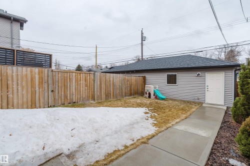 The property features a private yard with a wooden fence and a detached structure with siding, a window, and a white door - 9612 72 Avenue, Edmonton, AB - Outdoor