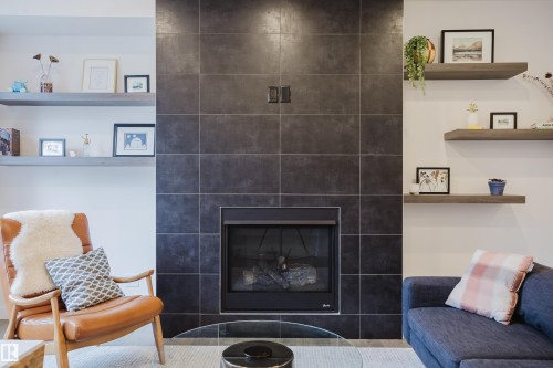 Living area featuring a tiled fireplace with an integrated firebox and hearth, flanked by built-in shelving - 9612 72 Avenue, Edmonton, AB - Indoor Photo Showing Living Room With Fireplace
