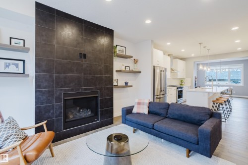 The living area features a dark tiled fireplace, open shelving, and recessed lighting - 9612 72 Avenue, Edmonton, AB - Indoor Photo Showing Living Room With Fireplace