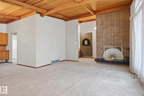 Living area featuring a wood-paneled ceiling, a brick accent wall with a fireplace, and light-colored carpeting - 9131 74 Street, Edmonton, AB - Indoor Photo Showing Other Room